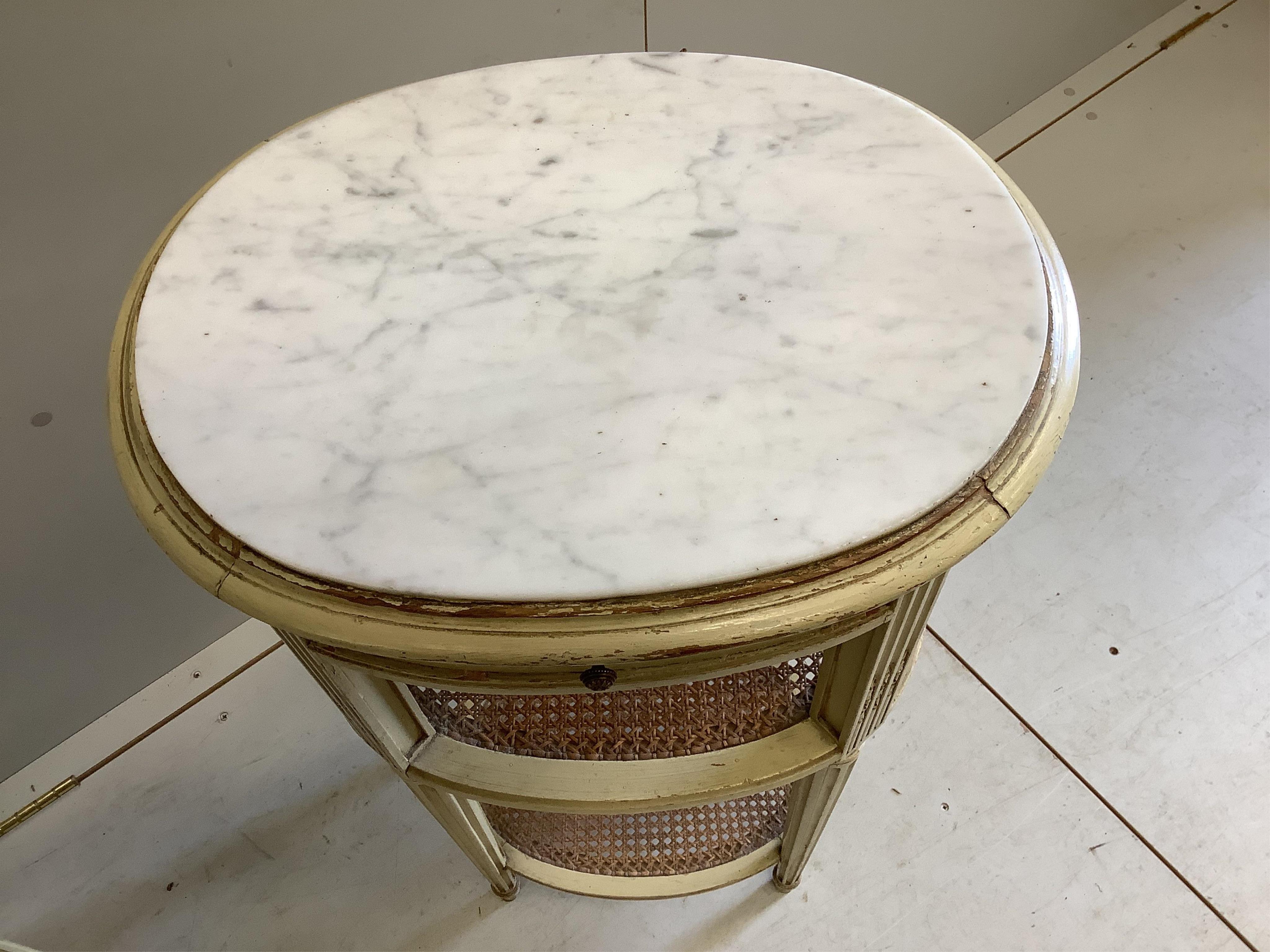 A pair of French cream painted bedside cabinets with oval marble inset tops, one fitted with a pot cupboard, width 44cm, height 83cm. Condition - fair, some differing to the marble